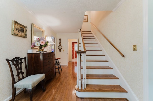 staircase with hardwood / wood-style flooring, crown molding, and a textured ceiling