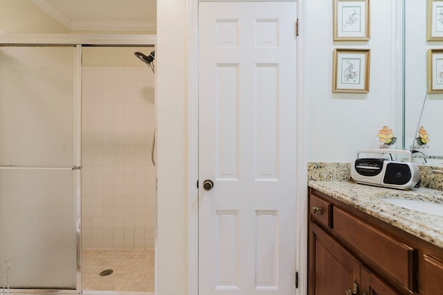 bathroom with a shower with door, vanity, and ornamental molding