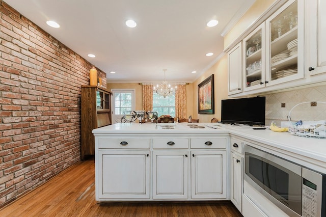 kitchen with white cabinetry, hanging light fixtures, and brick wall