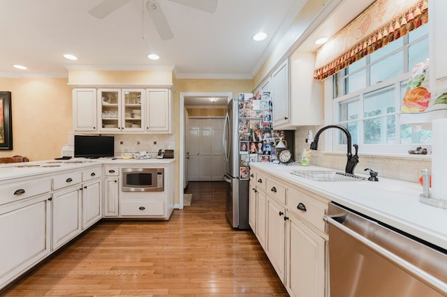 kitchen with sink, ornamental molding, stainless steel appliances, and white cabinets