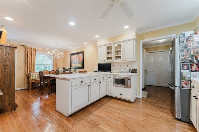 kitchen with decorative light fixtures, light wood-type flooring, kitchen peninsula, stainless steel appliances, and white cabinets