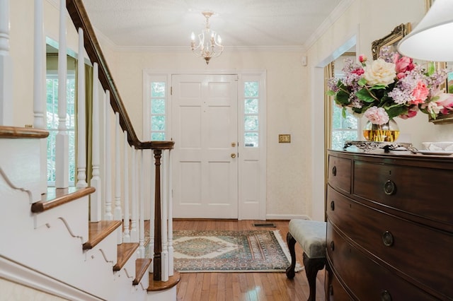 entrance foyer featuring crown molding, wood-type flooring, a textured ceiling, and a chandelier