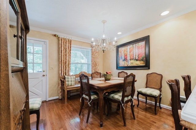 dining space with hardwood / wood-style flooring, crown molding, and an inviting chandelier