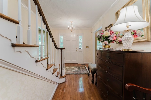 foyer featuring ornamental molding, a chandelier, hardwood / wood-style floors, and a textured ceiling