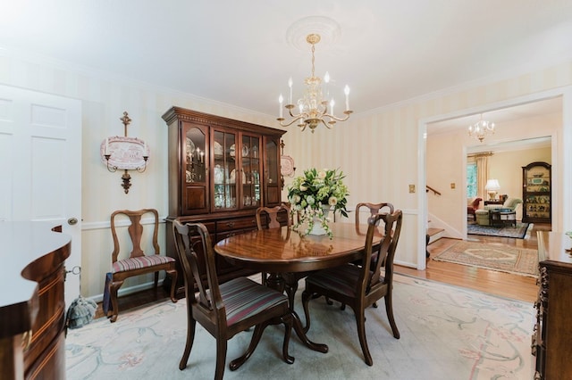 dining room with ornamental molding, a chandelier, and light hardwood / wood-style floors