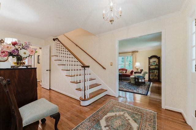 staircase with an inviting chandelier, hardwood / wood-style floors, and ornamental molding