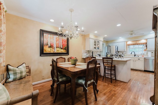 dining area featuring ceiling fan, ornamental molding, sink, and light wood-type flooring