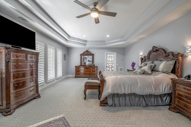 bedroom featuring multiple windows, light colored carpet, a raised ceiling, and ceiling fan