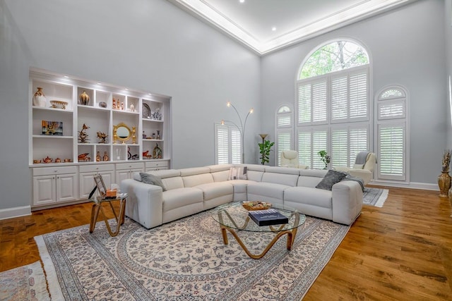 living room featuring a high ceiling, ornamental molding, and hardwood / wood-style floors