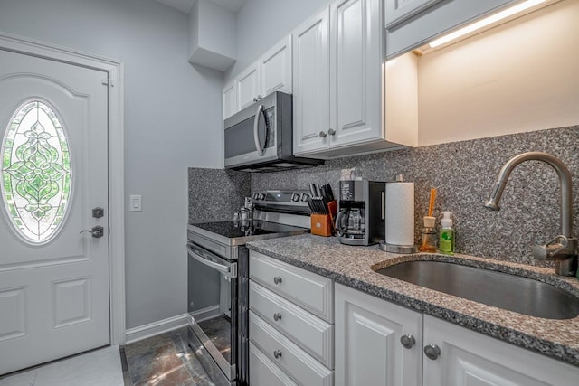 kitchen with stone counters, white cabinetry, sink, backsplash, and stainless steel appliances