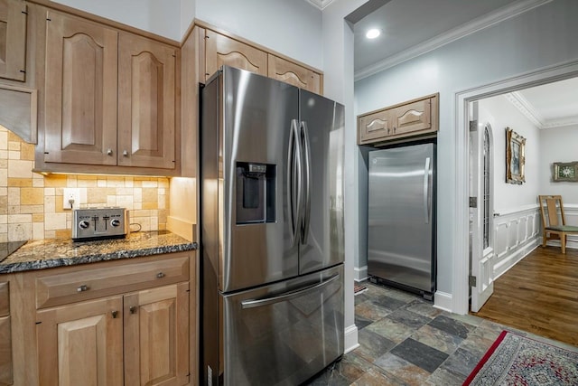 kitchen with tasteful backsplash, crown molding, stainless steel fridge, and dark stone counters