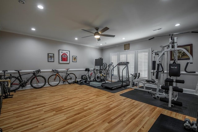 exercise room featuring ceiling fan, ornamental molding, and wood-type flooring