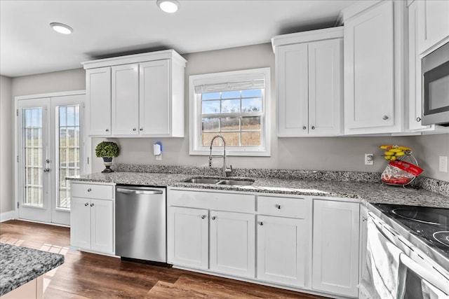 kitchen featuring appliances with stainless steel finishes, dark hardwood / wood-style floors, white cabinetry, sink, and light stone countertops