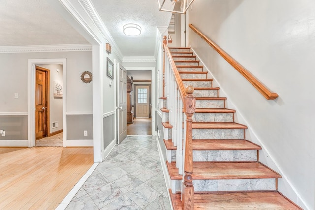 staircase featuring baseboards, visible vents, ornamental molding, and wood finished floors