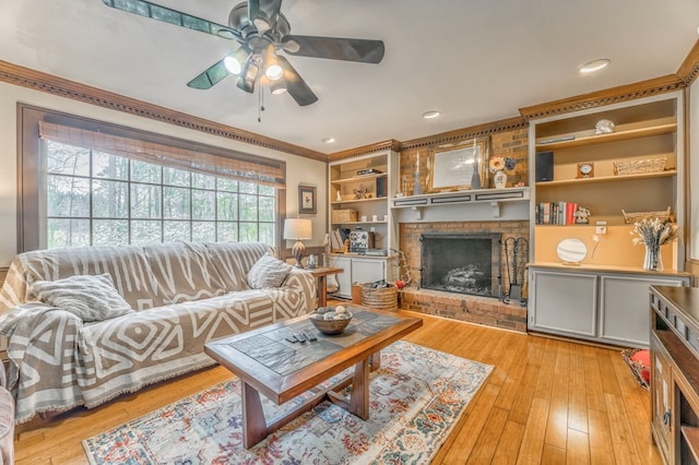 living area featuring light wood-type flooring, ornamental molding, ceiling fan, and a fireplace