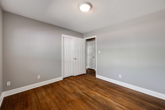 unfurnished bedroom with baseboards, wood finished floors, and a closet