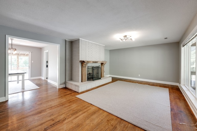 unfurnished living room featuring a fireplace, wood finished floors, and a wealth of natural light