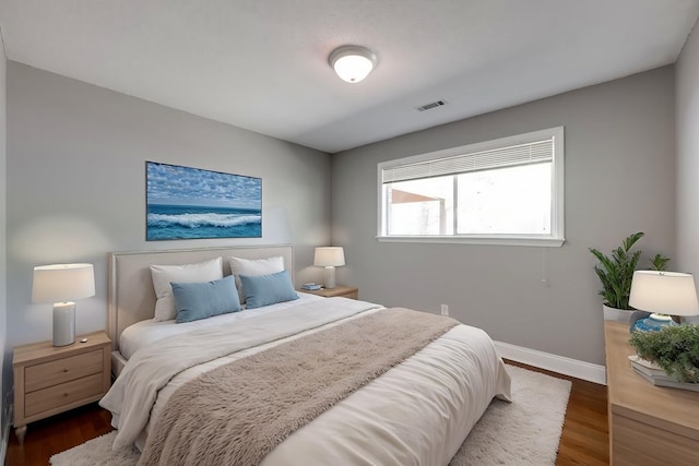 bedroom featuring baseboards, visible vents, and wood finished floors