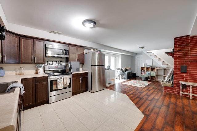 kitchen featuring visible vents, dark brown cabinetry, light wood-type flooring, light countertops, and appliances with stainless steel finishes