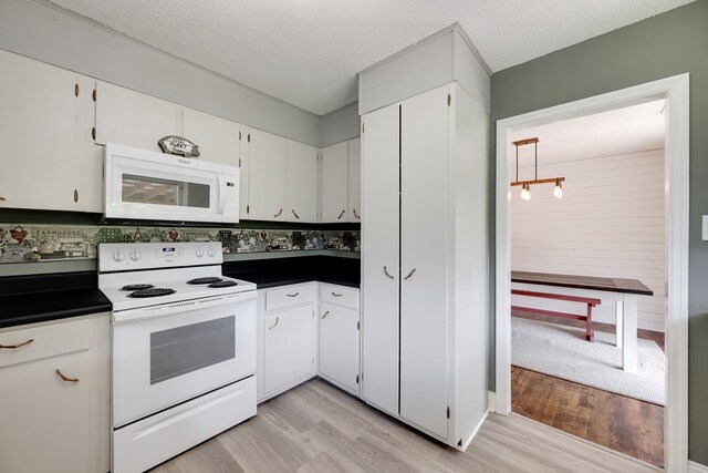 1113 Mount Vernon Rd, Tunnel Hill, GA 30755 - kitchen with white cabinets, dark countertops, light wood-style floors, white appliances, and a textured ceiling