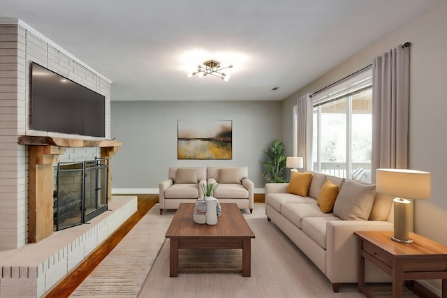 living area featuring light wood-type flooring, baseboards, and a fireplace