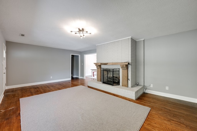 unfurnished living room featuring baseboards, a brick fireplace, wood finished floors, and visible vents