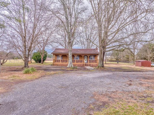 view of front of home featuring a porch, a storage unit, an outbuilding, and driveway