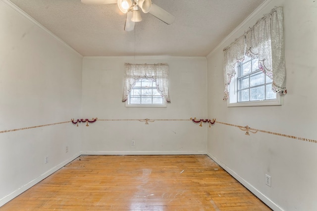 empty room with plenty of natural light, ornamental molding, a textured ceiling, and hardwood / wood-style flooring