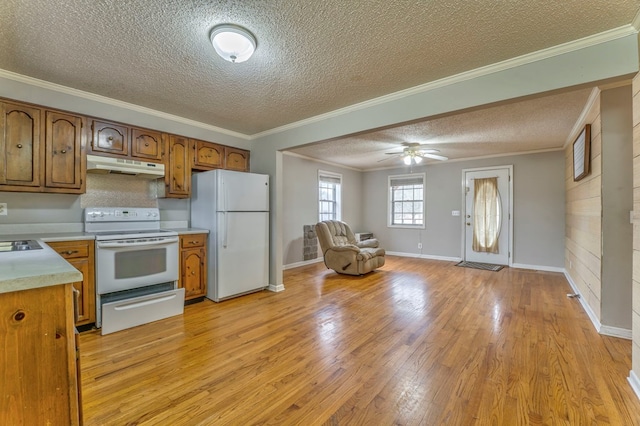 kitchen featuring white appliances, ornamental molding, light countertops, under cabinet range hood, and open floor plan