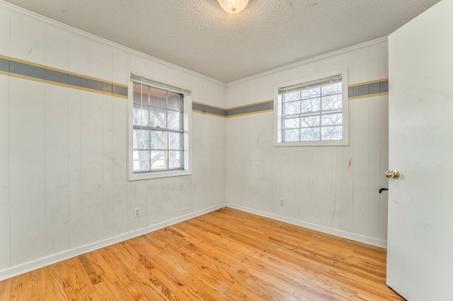 empty room featuring a wealth of natural light, a textured ceiling, and wood finished floors