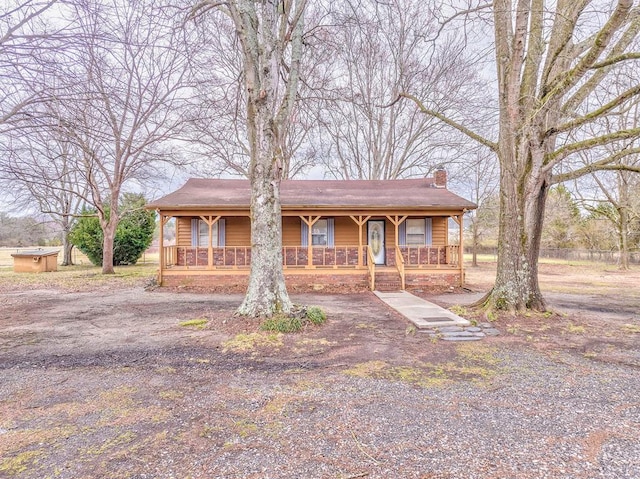 view of front of property with covered porch, driveway, and a chimney