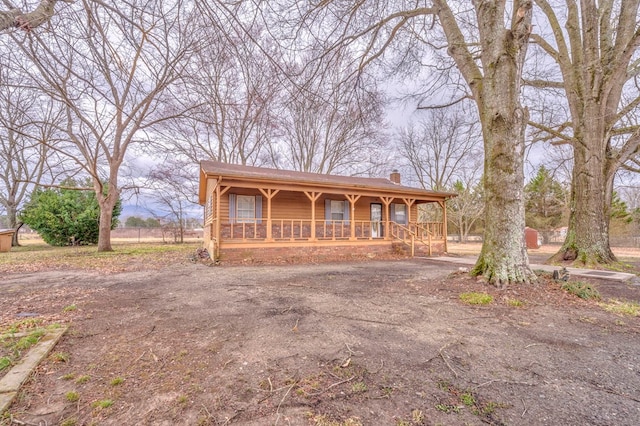 view of front of house with aphalt driveway, a porch, and a chimney