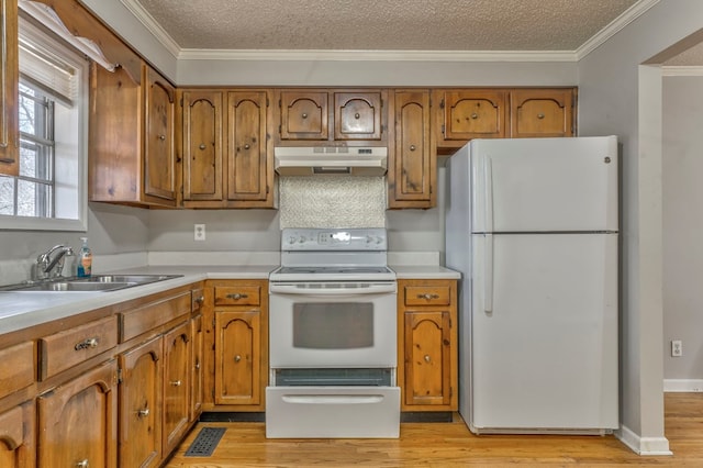 kitchen featuring crown molding, under cabinet range hood, brown cabinets, white appliances, and a sink