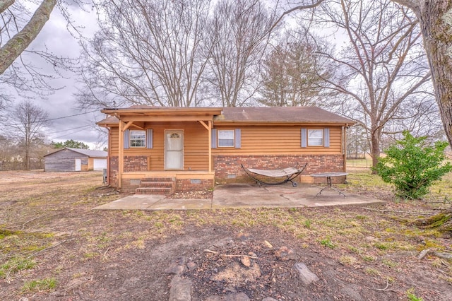 view of front facade featuring a patio, a porch, brick siding, and crawl space