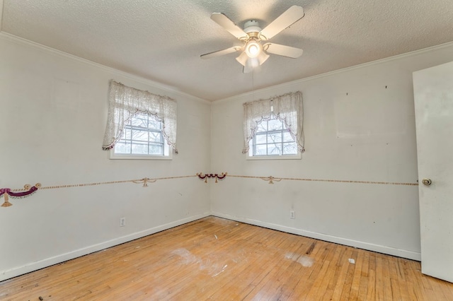 spare room with hardwood / wood-style floors, a textured ceiling, plenty of natural light, and ornamental molding