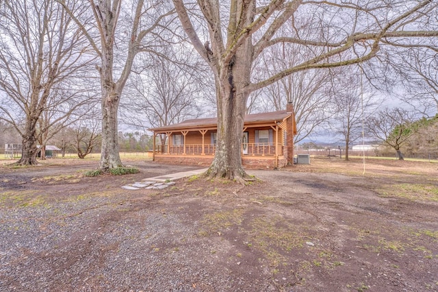 view of front of house with a porch, central AC, and a chimney