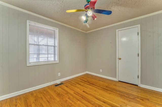 spare room featuring ceiling fan, visible vents, wood finished floors, and ornamental molding