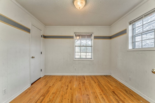 unfurnished room featuring ornamental molding, plenty of natural light, wood finished floors, and a textured ceiling