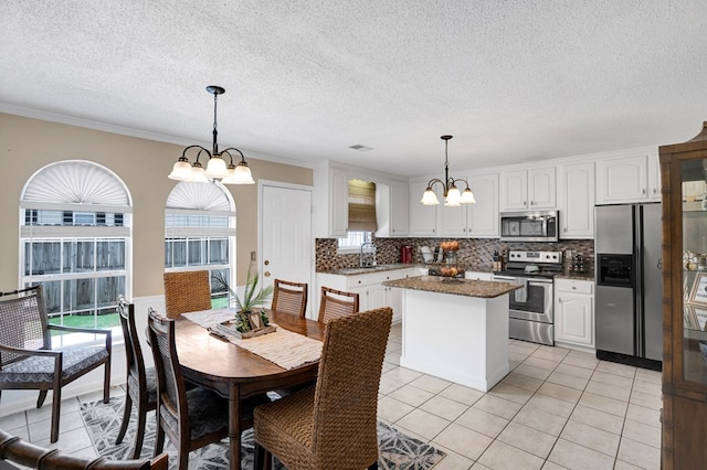 dining space with light tile patterned floors, crown molding, sink, and a chandelier