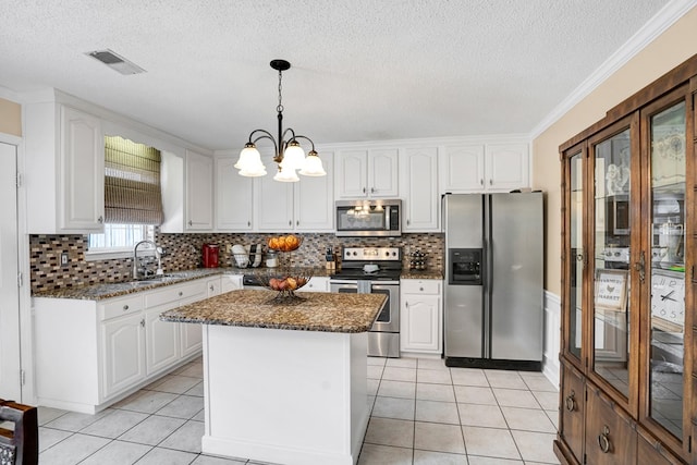 kitchen featuring appliances with stainless steel finishes, a kitchen island, a notable chandelier, pendant lighting, and white cabinets