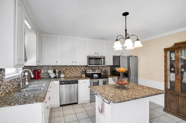 kitchen featuring decorative light fixtures, sink, white cabinets, a center island, and stainless steel appliances