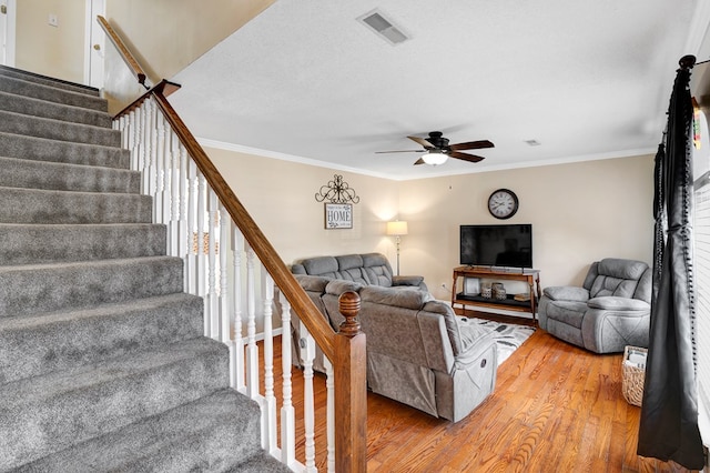 living room featuring ceiling fan, ornamental molding, wood-type flooring, and a textured ceiling