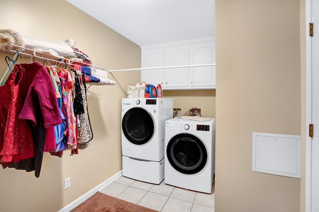 laundry room featuring cabinets, light tile patterned floors, a textured ceiling, and independent washer and dryer