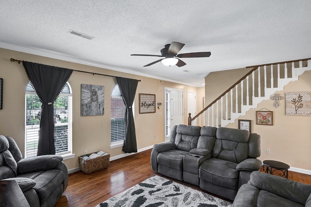 living room featuring dark wood-type flooring, ceiling fan, ornamental molding, and a textured ceiling