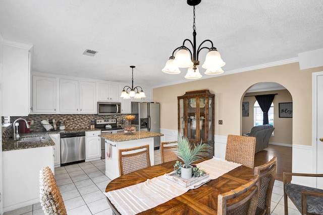 dining room featuring an inviting chandelier, crown molding, sink, and light tile patterned floors