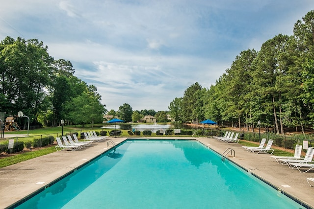 view of swimming pool featuring a water view and a patio