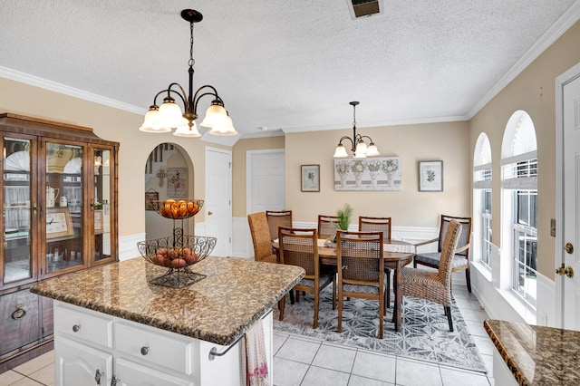 dining space featuring ornamental molding, light tile patterned floors, a notable chandelier, and a textured ceiling