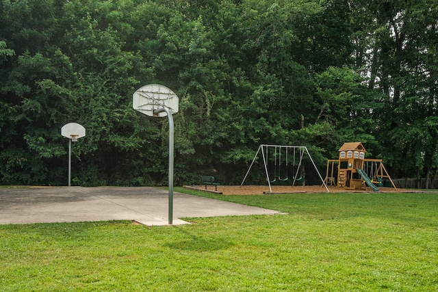 view of basketball court featuring a playground and a lawn