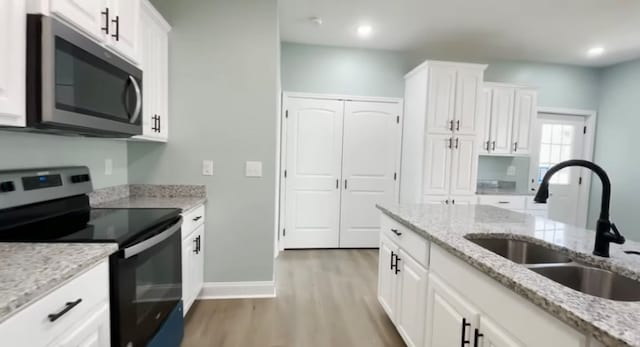 kitchen featuring light stone counters, sink, white cabinets, and appliances with stainless steel finishes