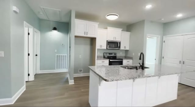 kitchen featuring sink, a kitchen island with sink, white cabinetry, electric range, and light stone countertops